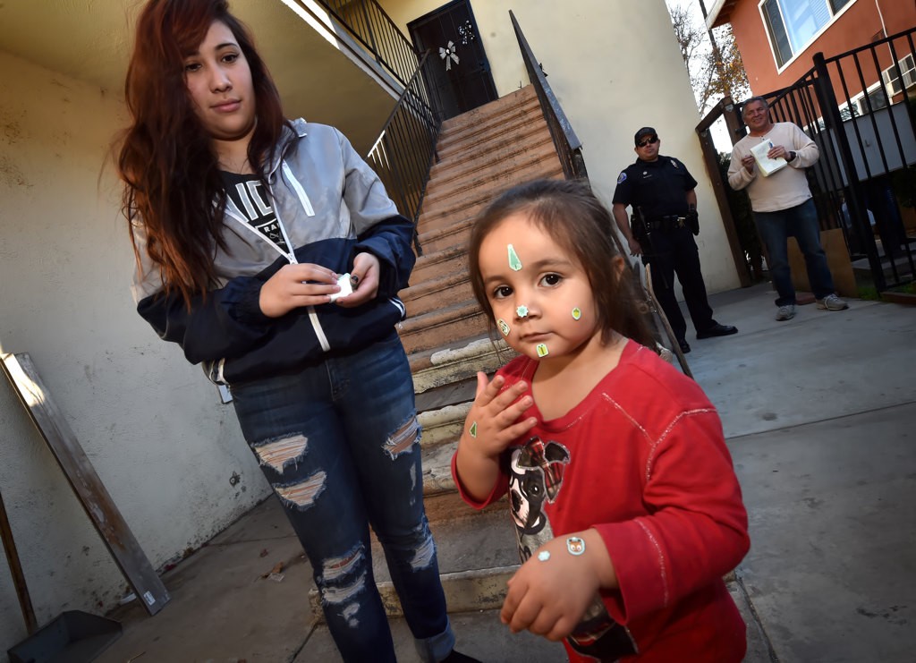 Mene Brones, 3, has stickers placed on her face by Michelle Carrillo, left, during a Palma Vista neighborhood barbecue. Photo by Steven Georges/Behind the Badge OC