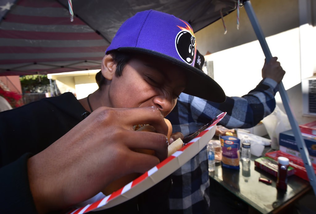 Edilson Cruz, 14, munches down on his chili dog during a neighborhood barbecue. Photo by Steven Georges/Behind the Badge OC