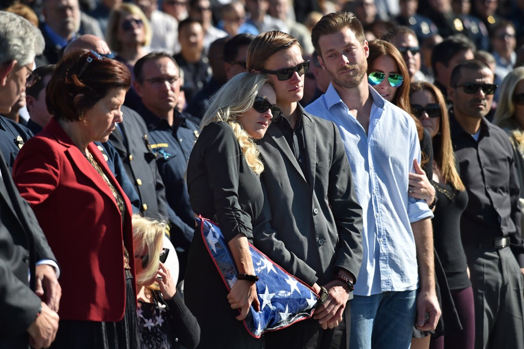 Melanie Weuve, wife of OCFA Capt. Eric Weuve, gives her son Parker, 14, a hug during a memorial service for his father. Photo by Steven Georges/Behind the Badge OC