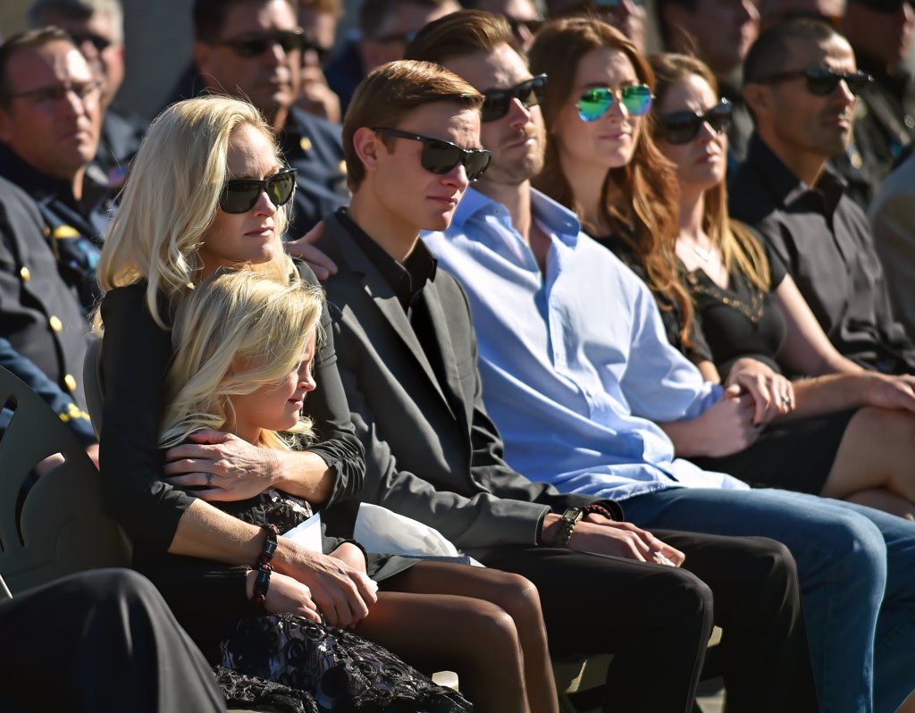 Melanie Weuve, wife of OCFA Capt. Eric Weuve, holds her daughter Brooklyn, 6, during a memorial service for Capt. Weuve. Next to her are her 14-year-old son Parker and Ryan McKibben, Eric’s half brother. Photo by Steven Georges/Behind the Badge OC