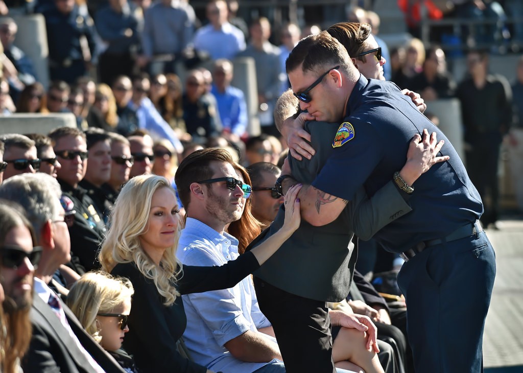 OCFA’s Jon Biegler gives Capt. Eric Weuve’s 14-year-old son Parker a hug during a memorial service. Capt. Weuve’s wife, Melanie, and daughter, Brooklyn, are left. Photo by Steven Georges/Behind the Badge OC