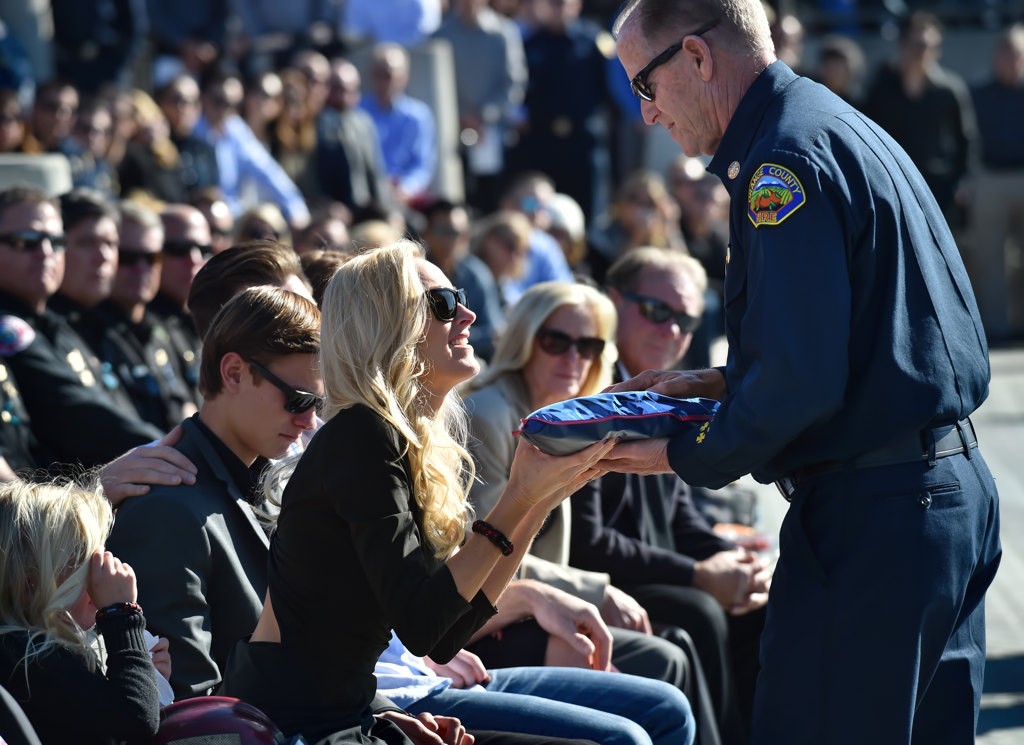 OCFA Fire Chief Jeff Bowman presents Capt. Eric Weuve’s wife, Melanie Weuve, a ceremonial flag during Capt. Weuve’s memorial service. Photo by Steven Georges/Behind the Badge OC