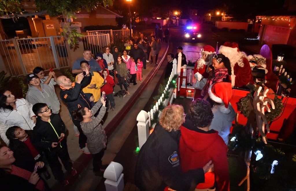 Parents take photos as their kids climb aboard Santa’s sleigh while it visits the neighborhoods of Tustin. Photo by Steven Georges/Behind the Badge OC