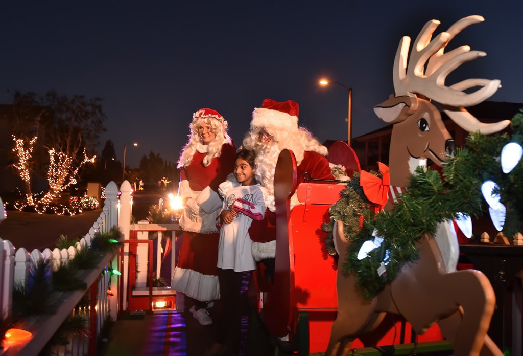 Kids from Tustin board the Santa sleigh trailer to have their photo taken as it rides through the streets of Tustin. Photo by Steven Georges/Behind the Badge OC