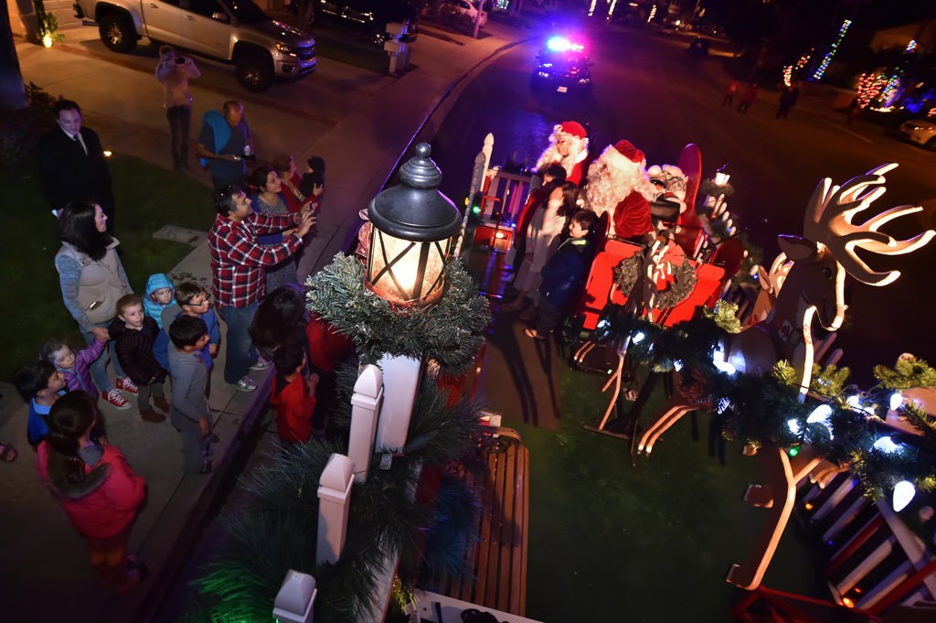 Parents take photos as their kids climb aboard Santa’s sleigh while it visits the neighborhoods of Tustin. Photo by Steven Georges/Behind the Badge OC