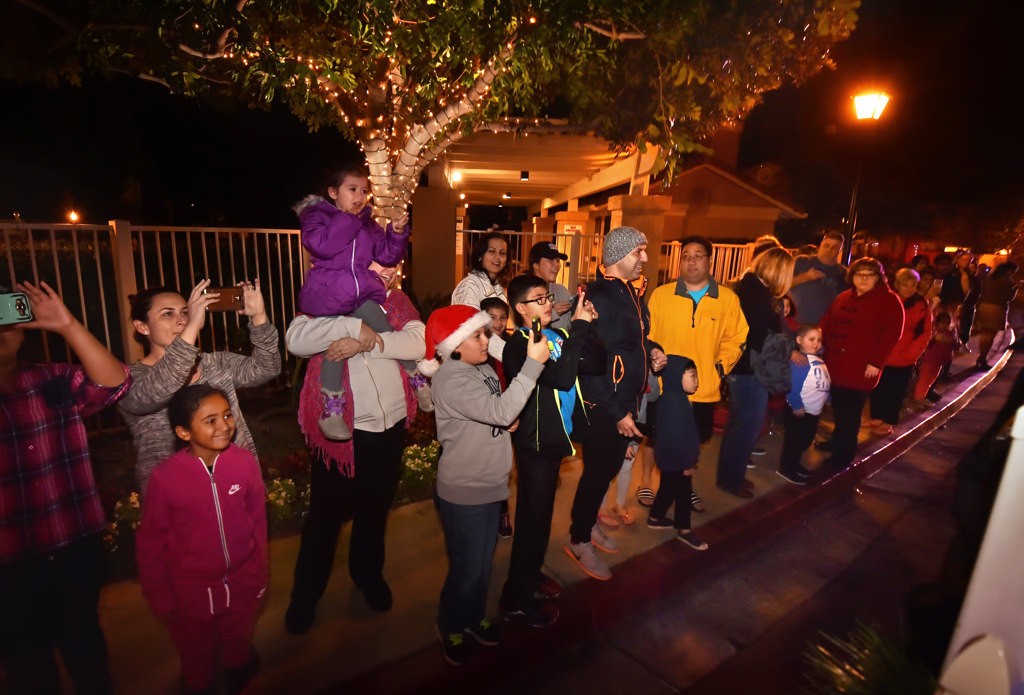 Kids wave and take photos as Santa’s sleigh arrives in their neighborhood. Photo by Steven Georges/Behind the Badge OC