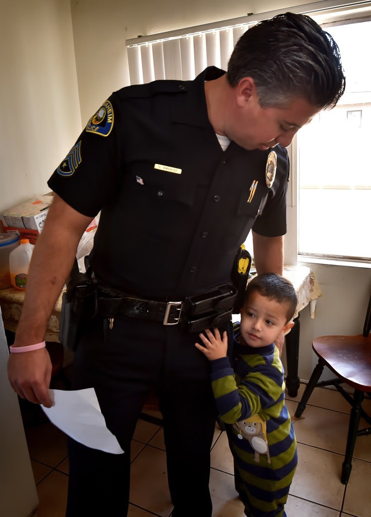 Anaheim PD Sgt. Danial Gonzalez gets a hug from 4-year-old Nathan Alcaraz after APD officers brought Christmas presents to their home. Photo by Steven Georges/Behind the Badge OC