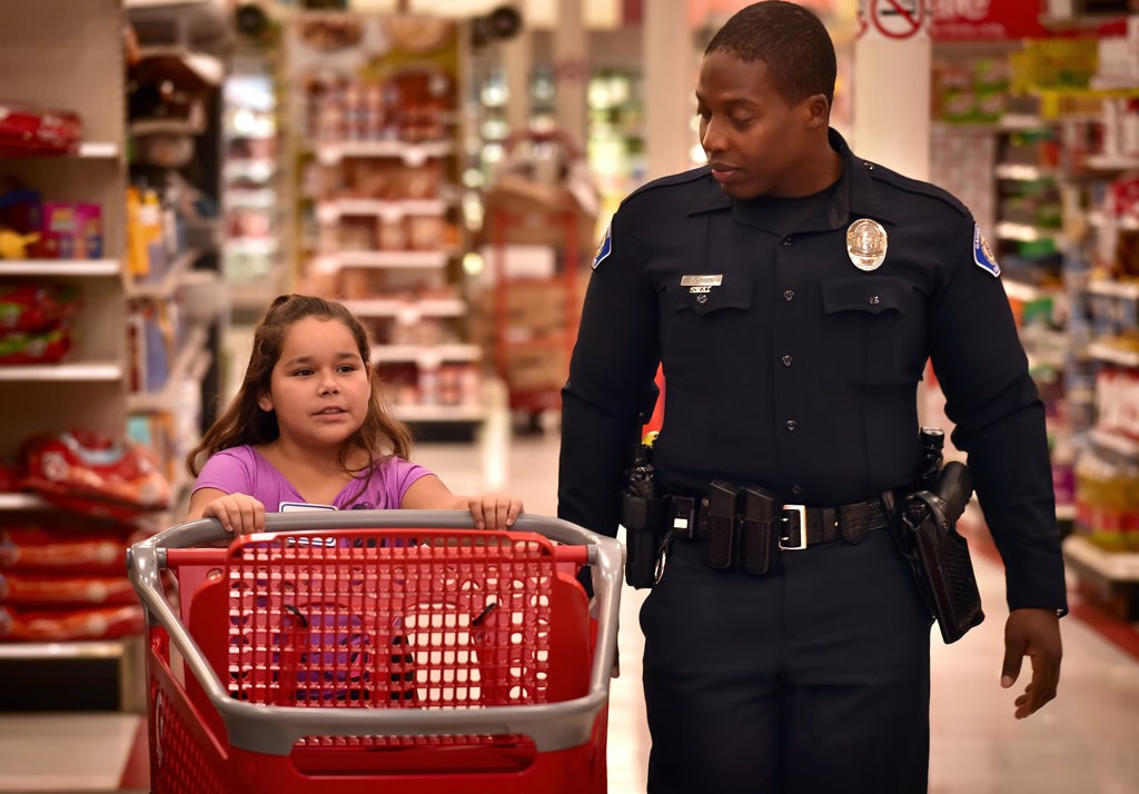 Garden Grove PD Officer Jason Johnson takes Janitzy, 9, through Target to help her shop for Christmas presents during the Shop with a Cop event. Photo by Steven Georges/Behind the Badge OC