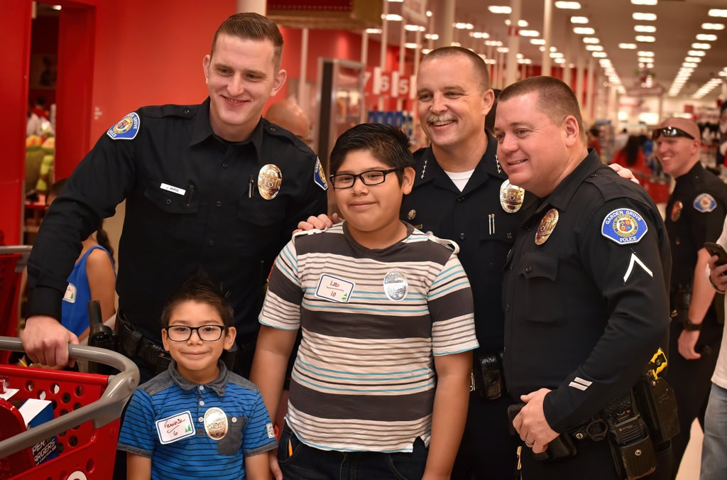 Frankie, 6, and Leo, 10, have their photo taken with Officer Jeremy Morse, left, Garden Grove Police Chief Todd Elgin and Officer Chuck Starnes during the GGPD’s Shop with a Cop event at Target. Photo by Steven Georges/Behind the Badge OC