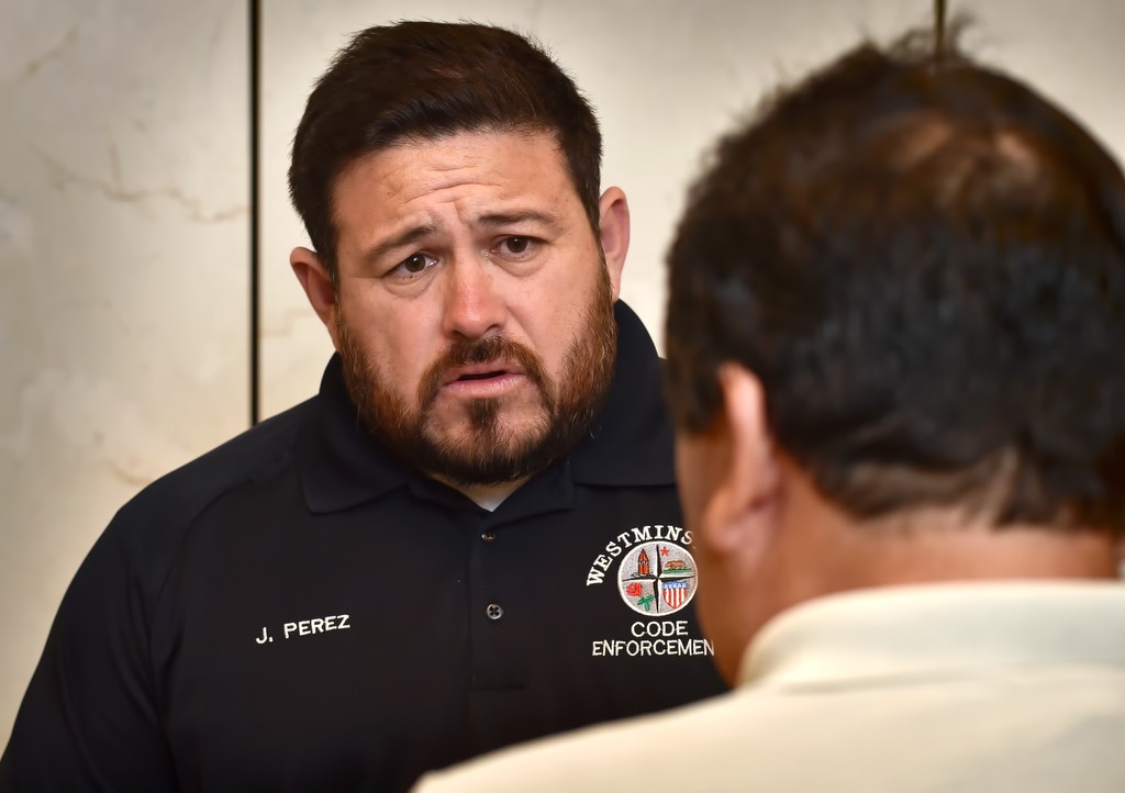 Westminster Code Enforcement Officer Jorge Perez helps a couple of citizens, in Spanish, who came walked in to police headquarters. Photo by Steven Georges/Behind the Badge OC