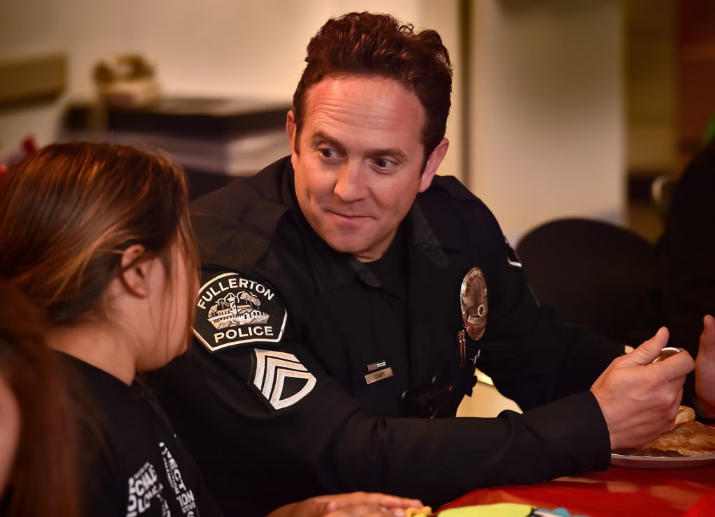 Fullerton PD’s Sgt. Joel Craft joins the kids as families sit down to a pancake and sausage breakfast during Fullerton PD”s Adopt a Family holiday program. Photo by Steven Georges/Behind the Badge OC