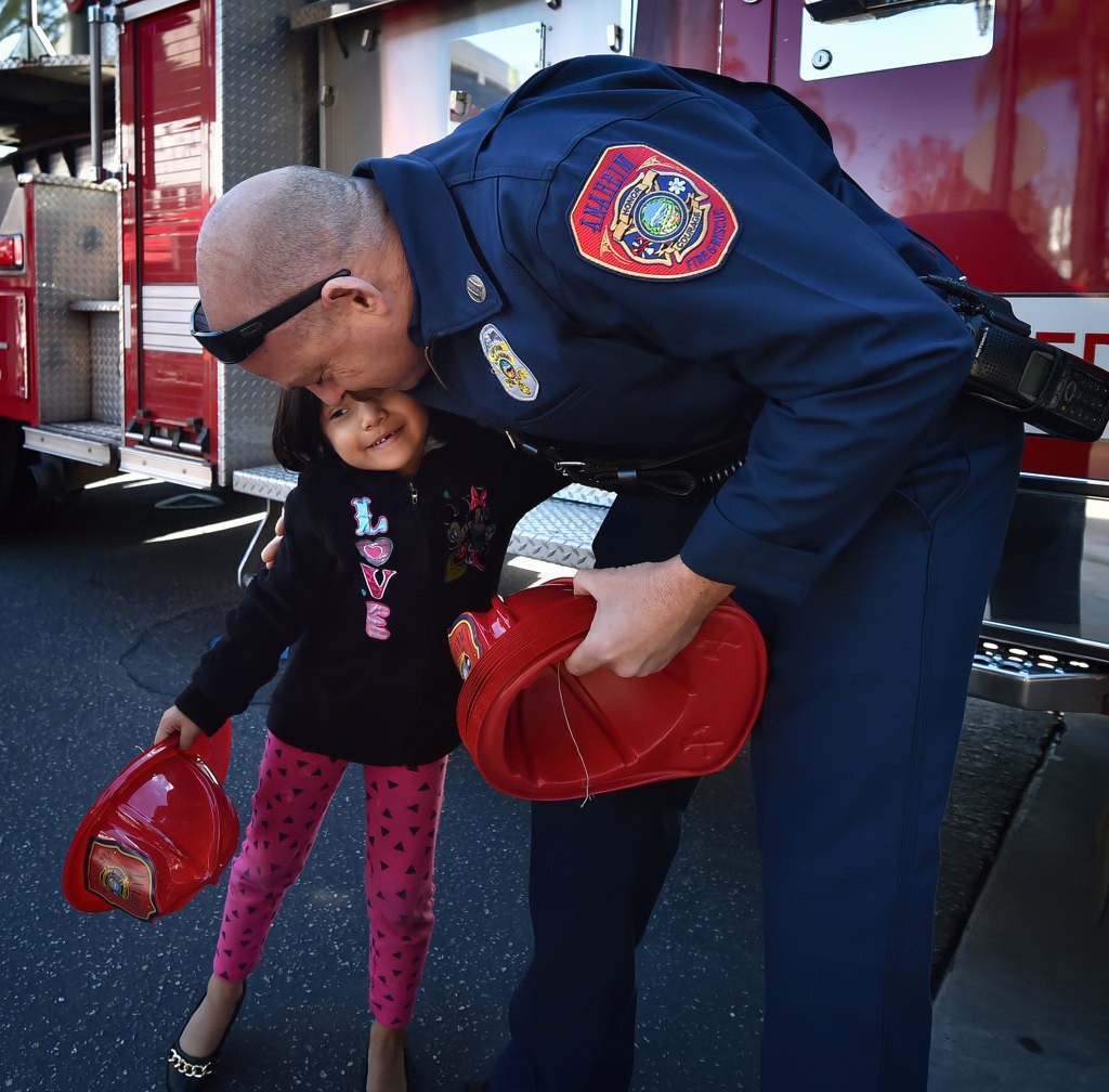 Capt. John Lesovsky of Anaheim Fire and Rescue gets a hug from Jocelyn Cabral, 5, after receiving her fire hat during Anaheim’s Community Holiday Brunch. Photo by Steven Georges/Behind the Badge OC