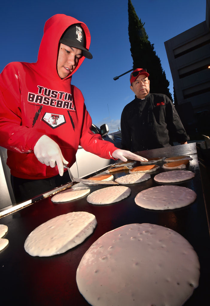 Mathew Elizalde, 16, of the Tustin High Baseball team, flips pancakes on the morning of Christmas Eve to help serve a free breakfast during Anaheim’s Community Holiday Brunch at the Center Street Promenade. Photo by Steven Georges/Behind the Badge OC