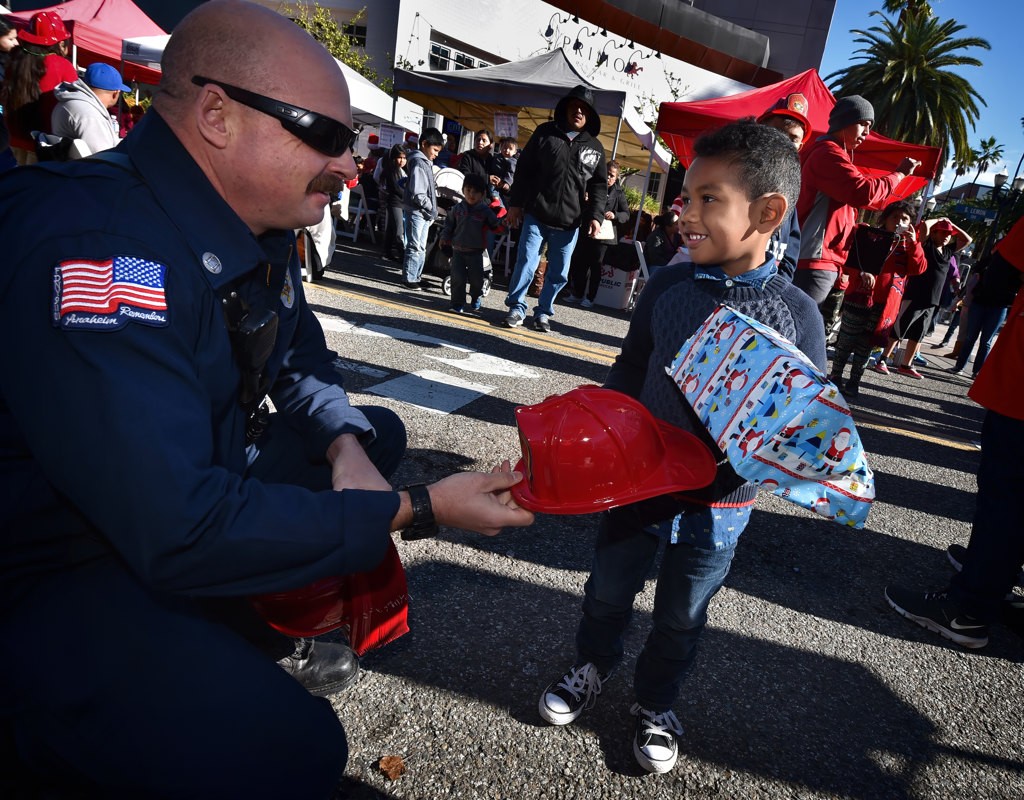 Capt. John Lesovsky of Anaheim Fire and Rescue hands out free fire hats to kids during  Anaheim’s Community Holiday Brunch. Photo by Steven Georges/Behind the Badge OC