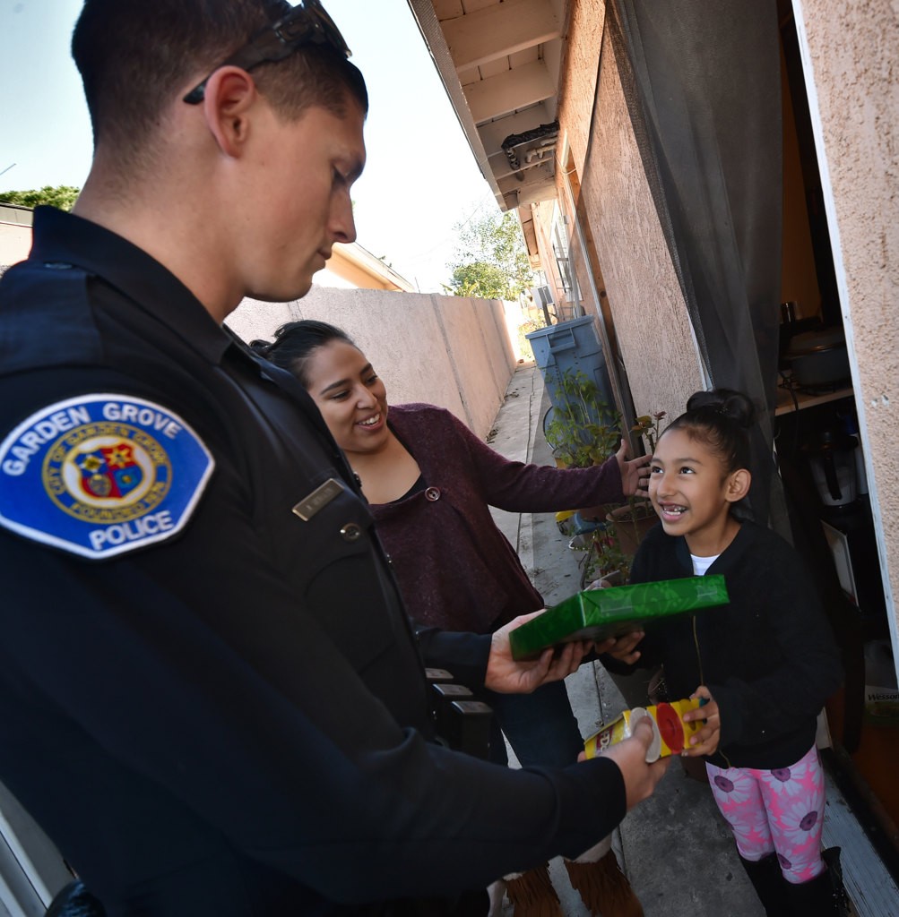 Seven-year-old April Perez looks up to thank Garden Grove PD Officer John Yergler as he hands her a Christmas present. Photo by Steven Georges/Behind the Badge OC
