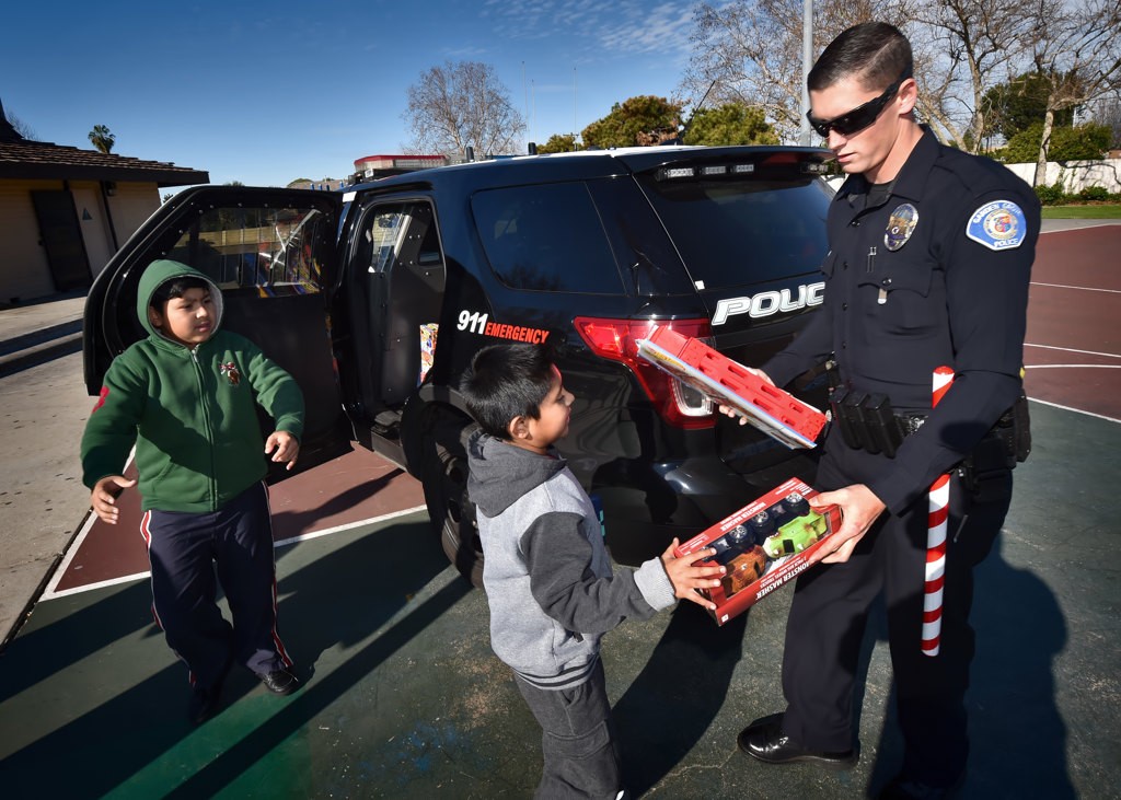 Garden Grove PD Officer John Yergler hands out donated presents to kids on Christmas morning at Woodbury Park in Garden Grove. Photo by Steven Georges/Behind the Badge OC