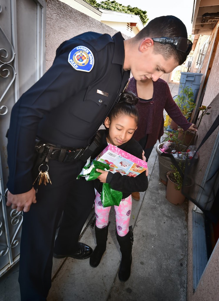 Garden Grove PD Officer John Yergler gets a hug from April Perez, 7, after receiving a donated present from him on Christmas morning. Photo by Steven Georges/Behind the Badge OC