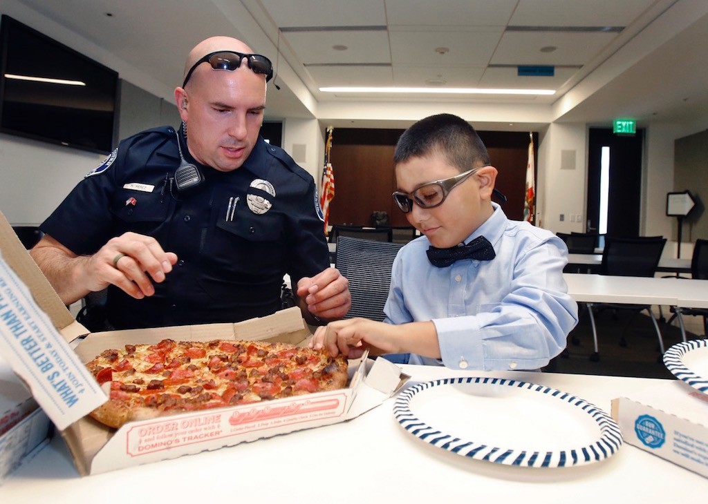 Westminster Officer Roland Perez and Mateo Sanchez, 9, grab a slice of pizza in the department's Emergency Operations Center. Photo by Christine Cotter/Behind the Badge OC. 