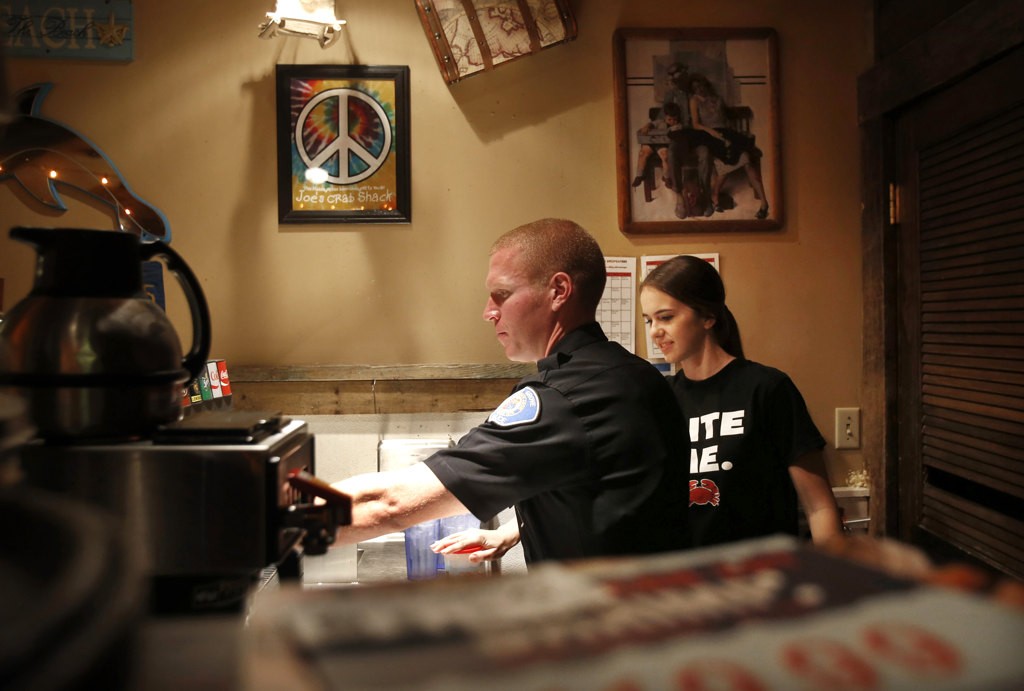 Waitress Kilee Holroyd supervises as Garden Grove Officer Chris Shelgren fills a drink order at Joe's Crab Shack in Garden Grove.  Photo by Christine Cotter