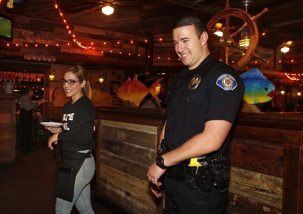 Garden Grove officer, Jeremy Morse, talks to diners at Joe's Crab Shack. Morse worked with waitress Kimberly Picone, left, during the fundraiser for the Special Olympics. Photo by Christine Cotter