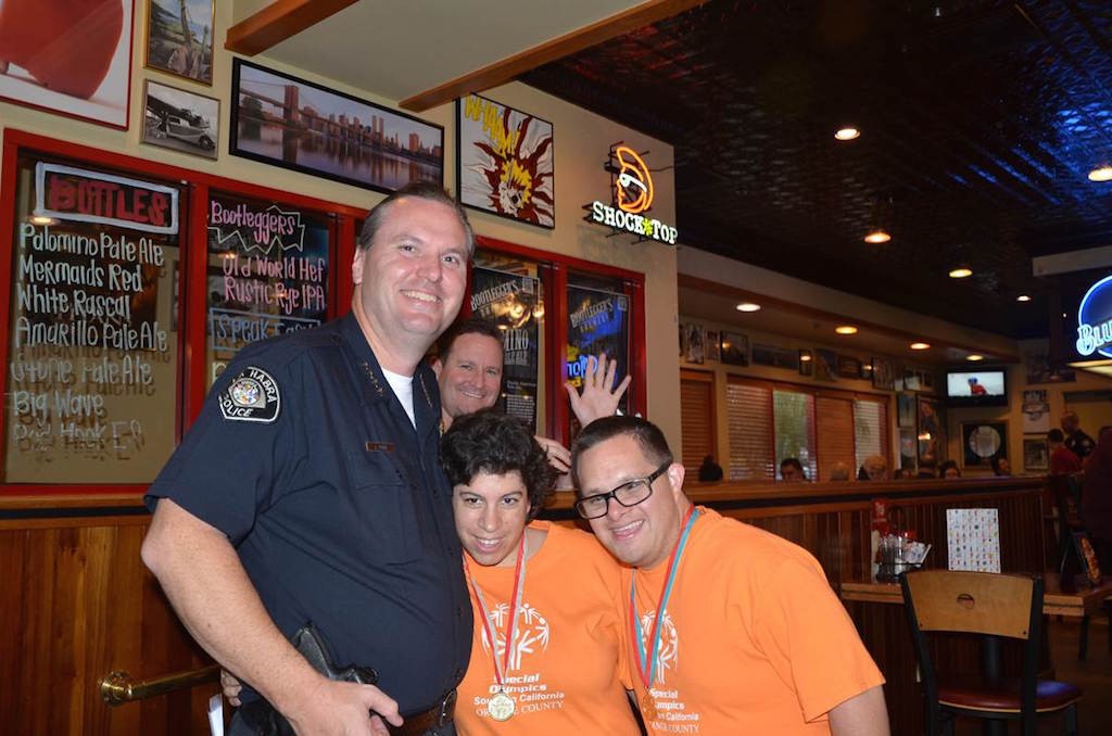 Chief Jerry Price and Capt. George Johnstone, background, pose for a quick photo with two Special Olympics athletes at a previous Tip a Cop even at Red Robin. Photo courtesy La Habra PD. 
