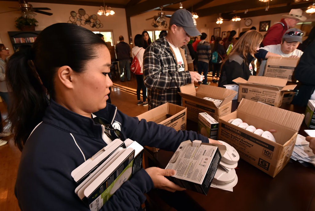 Disney volunteer Lisa Kanazawa, left, works with her team unpacking smoke detectors in preparation of installing them at the Friendly Village Mobile Home Park in Anaheim. Photo by Steven Georges/Behind the Badge OC
