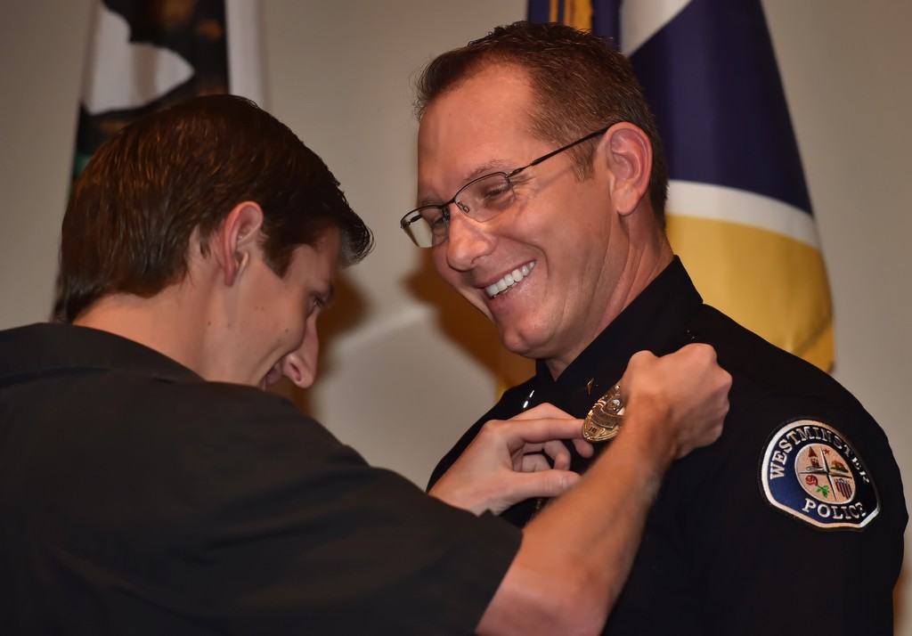 Commander Mark Lauderback smiles as he receives his new badge from his son, Brett Lauderback, 20, during a Westminster PD promotion ceremony. Photo by Steven Georges/Behind the Badge OC