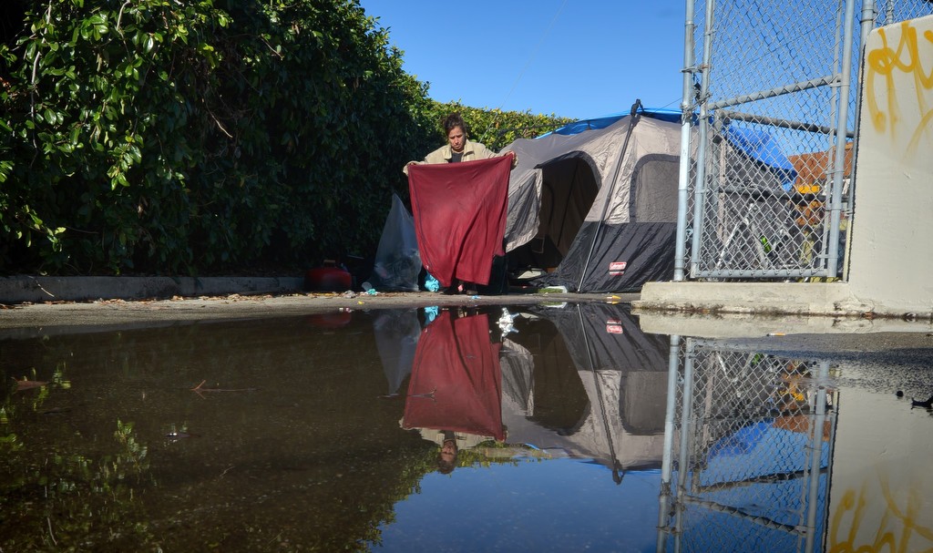 A puddle of water left over from the recent rains sits near a tent in Fullerton where a couple of homeless women currently stay. Photo by Steven Georges/Behind the Badge OC