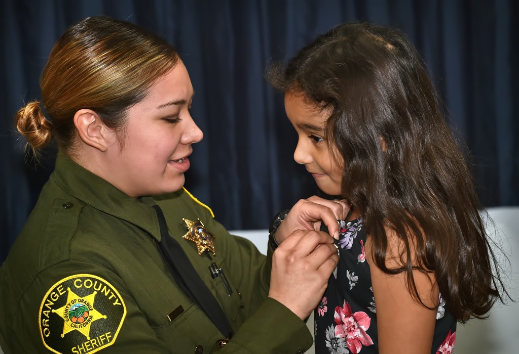 After receiving her new OCSD deputy badge from her daughter, Deputy Melinda Reyna pins a smaller version of that badge on her daughter, Olivia Torres, on her 7th birthday. Photo by Steven Georges/Behind the Badge OC