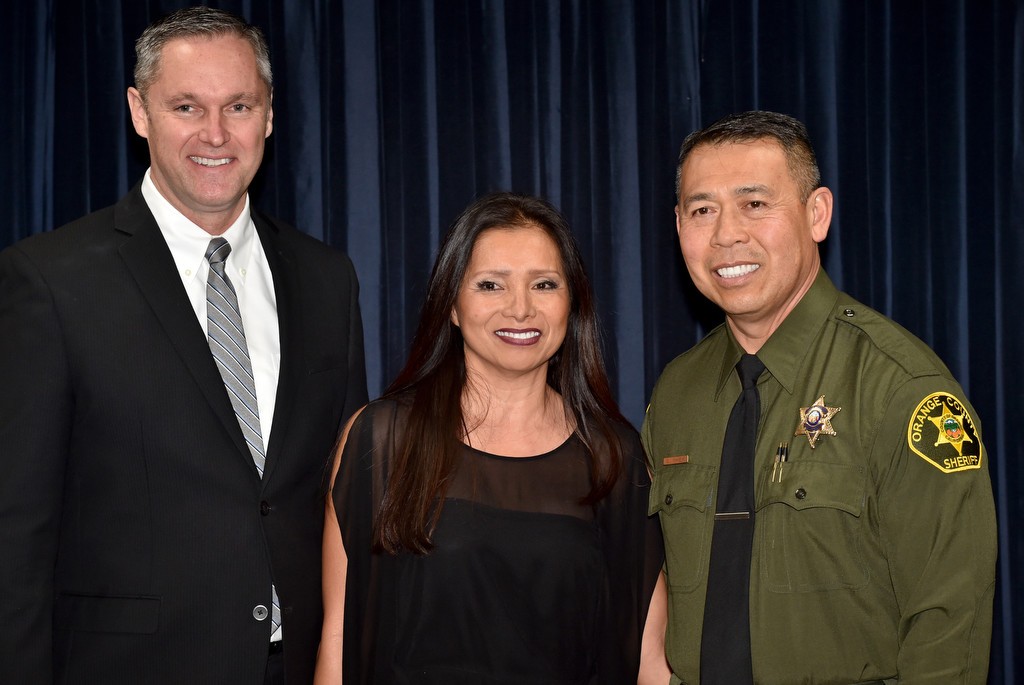 Deputy Steve Nhek, right, stands with his wife, Julia Nhek, and Undersheriff Don Barnes, left, after receiving his new badge during a swearing in ceremony for laterals at the OCSD. Photo by Steven Georges/Behind the Badge OC
