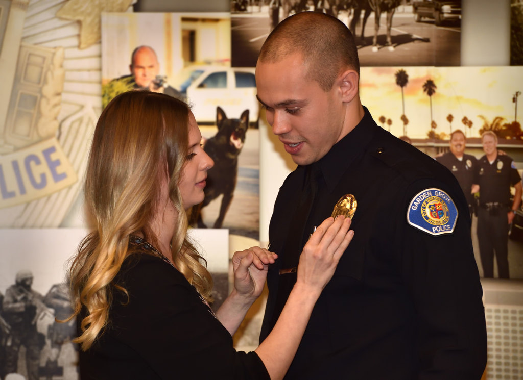 Joshua Brannon, a lateral from Los Angeles PD, gets his new Garden Grove PD badge pined to him by his wife Sara Brannon during a swearing in ceremony. Photo by Steven Georges/Behind the Badge OC