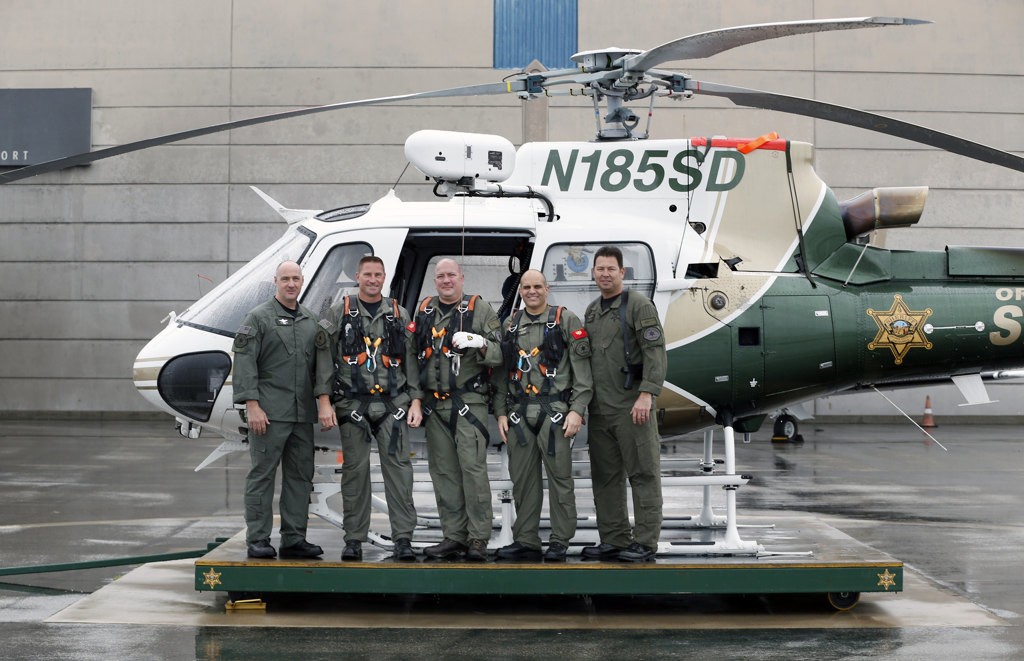 Orange County SheriffÕs Department helicopter crew members, R.J. Garwood, Jim Slikker, Joe Kantar, Michael De Laby and Bill Fitzgerald, from left, in front of one of their rescue helicopters stationed at John Wayne Airport. Photo by Christine Cotter
