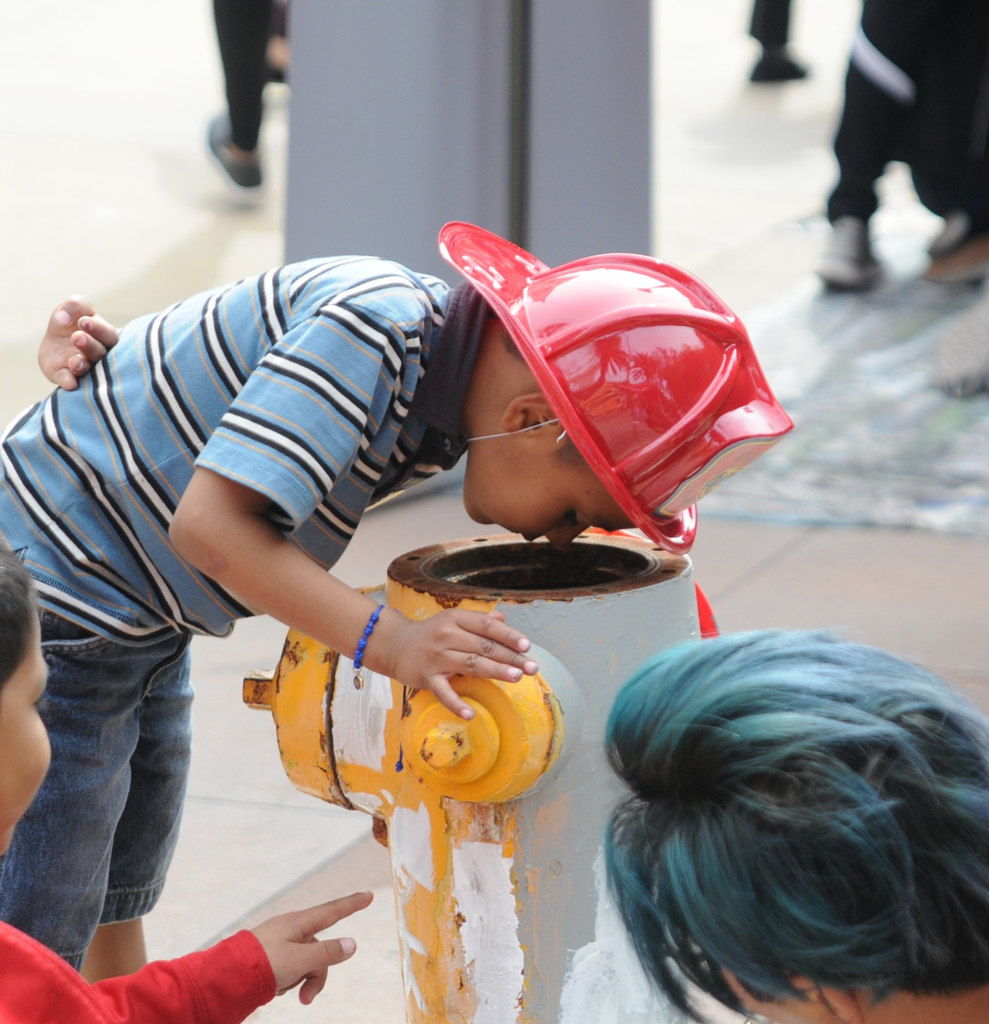 A youngster, perhaps a future Anaheim firefighter, is curious about the inside of a fire hydrant. Photo by Lou Ponsi/Behind the Badge