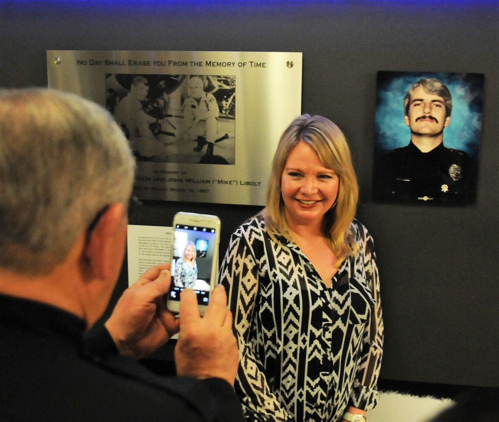 Katie Libolt, daughter of Costa Mesa police officer Mike Libolt, poses for picture in front of photo of her father, who was killed in the line of duty along with his partner Dave Ketchum on March 10, 1987. A memorial honoring the two officers was unveiled March 10, the 30th anniversary of the tragedy.