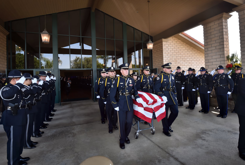 Honor guards, including Tustin PD and Orange County Sheriff Department, salute as the casket holding Whittier PD Officer Keith Boyer is carried out and placed in the hearse at the conclusion of a memorial service at Calvary Chapel Downey. Photo by Steven Georges/Behind the Badge OC
