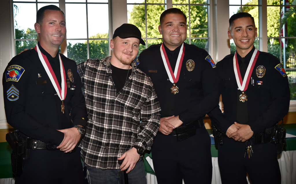 Orange PD Officer Sharif Muzayen, second from left, stands with fellow Orange officers who helped save his life after being hit by a drunk driver. From left is Sgt. Kevin Plog, Officer Muzayen, Officer Jesse Ochoa and Officer Ivan Alvarez. Photo by Steven Georges/Behind the Badge OC