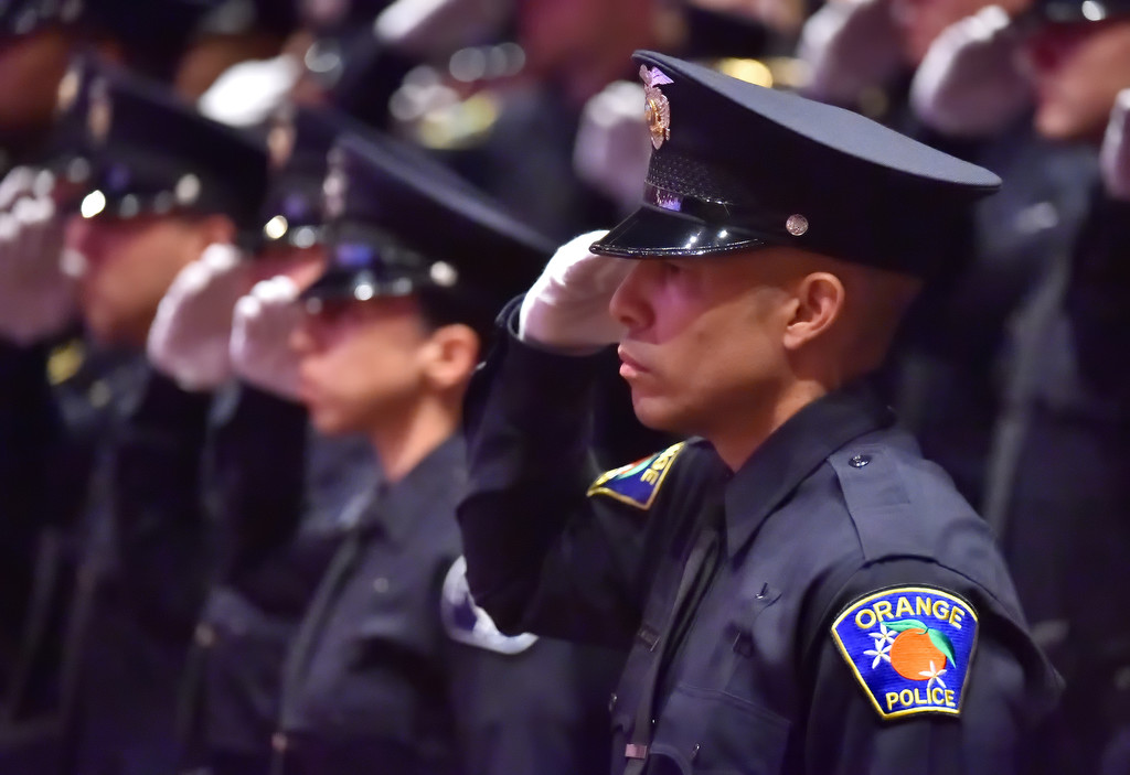 Orange PD Recruit Eric Velazquez, right, salutes during the Pledge of Allegiance at the start of the GWC police academy graduation ceremony. Photo by Steven Georges/Behind the Badge OC