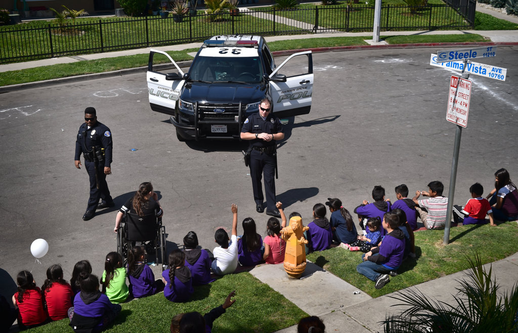 Garden Grove PD officers Ralph Lee, left, and Taylor Macy talks to kids at the Palma Vista neighborhood about teamwork in keeping the neighborhood safe for kids. Photo by Steven Georges/Behind the Badge OC