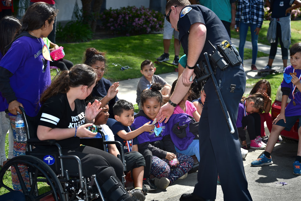 Garden Grove PD Officer Taylor Macy hands out GGPD stickers to kids during the Junior Neighborhood Watch Club kick-off event. Photo by Steven Georges/Behind the Badge OC